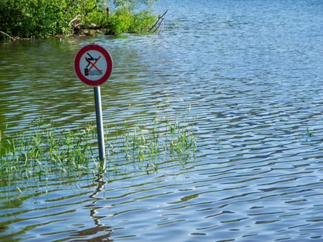 Blick auf ein vom Hochwasser im Grüntensee umgebenes Verkehrszeichen nahe dem Seeufer mit der Bedeutung nicht in das Wasser Springen.