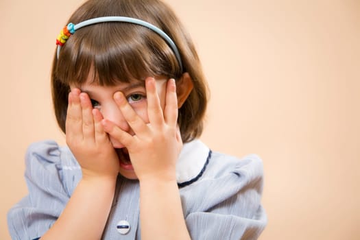 little girl gazing through her fingers, astonished