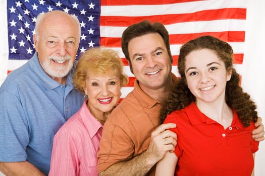 Grandparents, their adult child, and their granddaughter, posing in front of an American Flag.