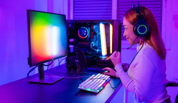 Winning Victory. Asian gamer playing online video game excited on desktop computer PC colorful neon LED lights, young woman in gaming headphones using computer she happy successful, E-Sport concept