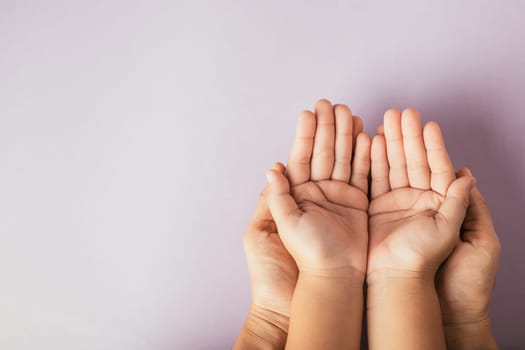 Top view parents and little kid holding empty hands together studio shot isolated on pink background, family home, hands children on adult mother hand, help support, parents family day concept