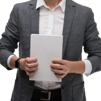 A man in a blazer stands holding blank sheets of paper in both hands, presenting a professional demeanor in a neutral setting.
