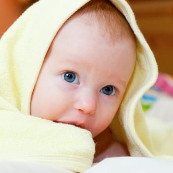 Little baby girl lying under yellow towel