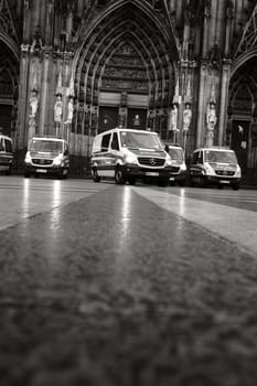 Grayscale shot of many Mercedes-Benz Sprinter police cars in front of Cologne Cathedral in Germany
