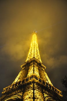 Low angle view of the majestic Eiffel Tower at cloudy night, Paris, France