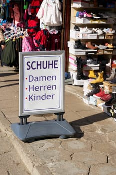 Sign with German text at a market in Swinoujscie, Poland. Translation on the sign: shoes for ladies, men, children