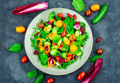 Summer delicious salad of tomatoes, cucumbers, peppers and spinach.