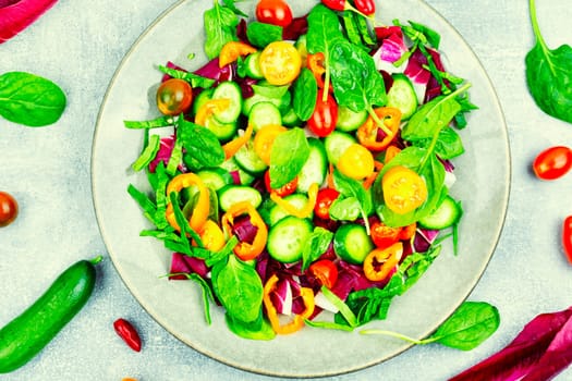 Summer delicious salad of tomatoes, cucumbers, peppers and spinach.