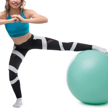 A woman in workout attire demonstrates a balance exercise on a fitness ball, showcasing strength and stability in a bright setting.