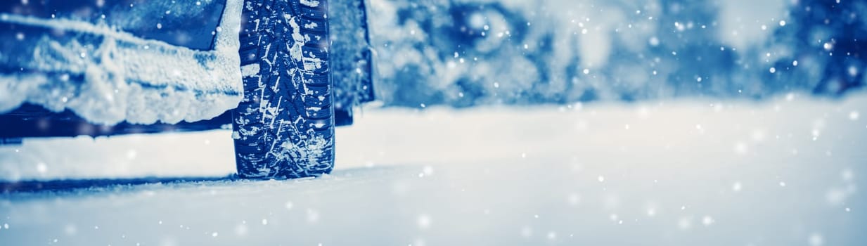 Closeup view of the car's wheel on the snowy road in natural park. Beautiful panoramic view.