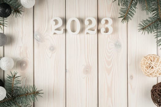 Light wooden wallpaper 2023 with fir tree, balls and Christmas toy decoration. Happy new year and merry xmas, holiday event celebration. Evergreen tree frame for greetings. Copy space, top view