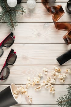 Vertical composition frame scattered popcorn, 3d glasses, film, fir, garland and remote control on wooden background. Time to watch movies, premier and modern technology. Top, flat lay, copy space