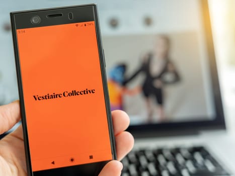 Milan, Italy - 10 13 2021: Installing Vestiaire Collective app for smartphone, with laptop.