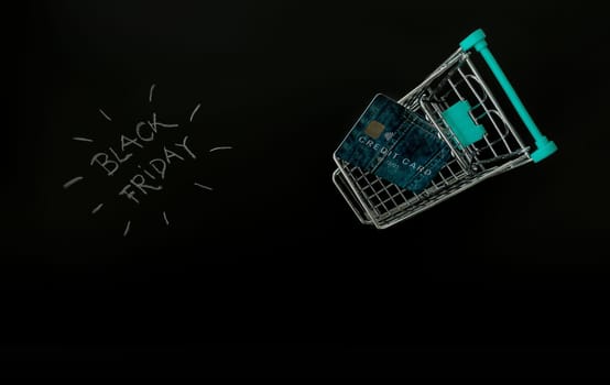 Black Friday advise with shopping trolley, credit card and black background.