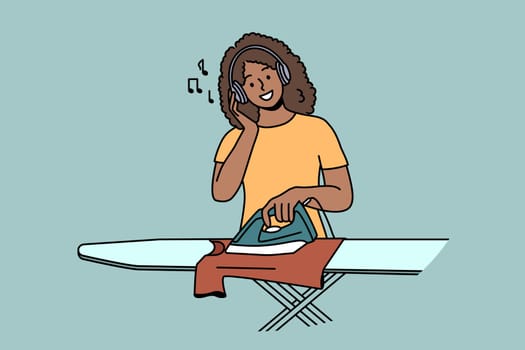 Smiling young woman in headphones ironing clothes at home. Happy African American girl listen to music in earphones do house chores. Vector illustration.