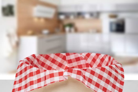 Empty picnic basket. Close-up of a empty straw basket with a checkered red napkin on table over blurred kitchen background. For your food and product display montage.