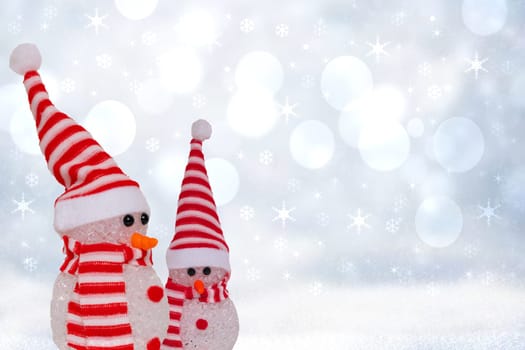 Christmas greeting card template. Xmas background texture with two cute winter snowman with red white striped hat and scarf in a abstract snowy winter landscape. Space.