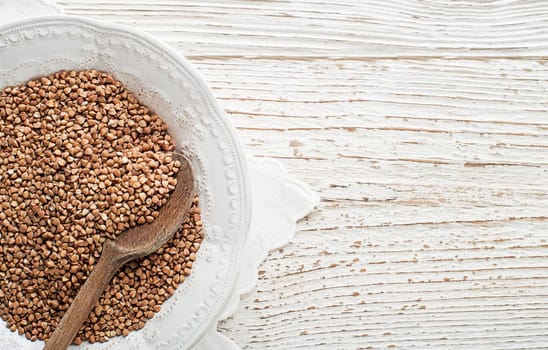 Healthy buckwheat cereal grains with spoon close up.