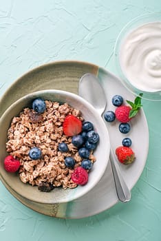 A bowl of dry granola served with fresh berry fruit and yogurt. Oatmeal plate. Healthy food, diet. Top view.