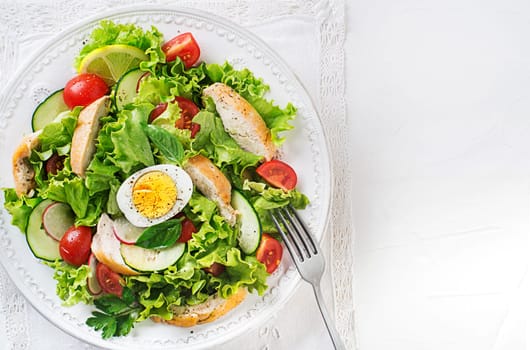 Fresh green salad with chicken breast vegetable and boiled egg on white background close up