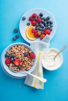 A bowl of dry granola served with fresh berry fruit and yogurt. Oatmeal plate. Healthy food, diet. Top view.