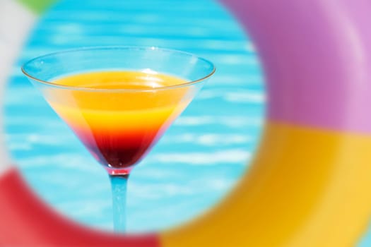 Colorful cocktail in front of attractive blue pool water