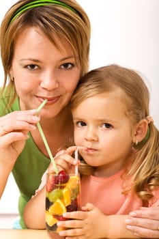 Woman and little girl sharing a fruity refreshment