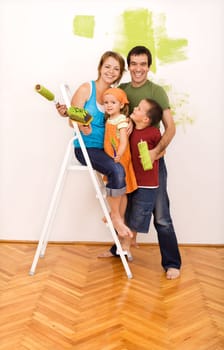 Happy family with two kids on a ladder painting their new home together