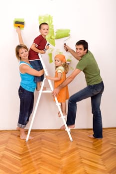 Happy family with two kids holding brushes and painting rolls redecorating their home together