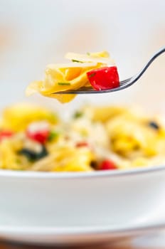 Tortellini primavera garnished with basil leaves on white plate
