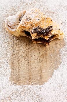 A half eaten chocolate croissant sprinkled with sugar