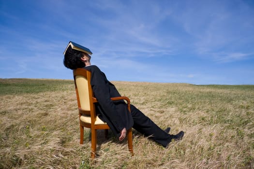 Business man with a book on his head having a rest on the nature