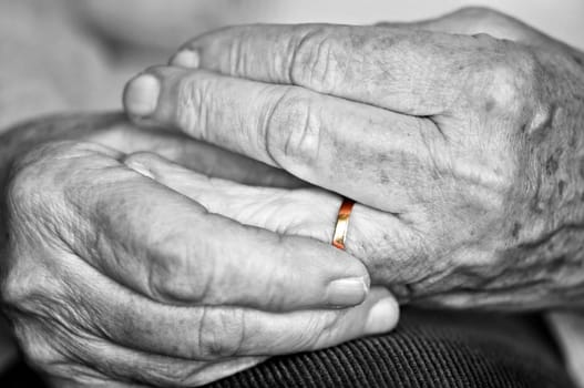 Close up on elderly woman hands with golden wedding ring