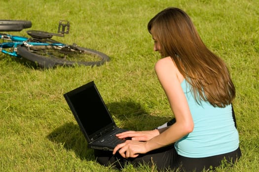 female student with laptop learning on the grass