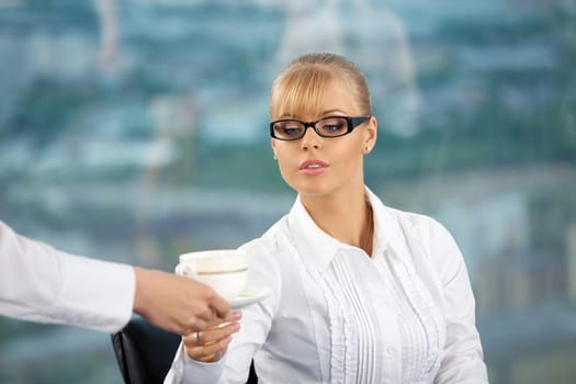 Someone brings the beautiful business lady a coffee cup at office