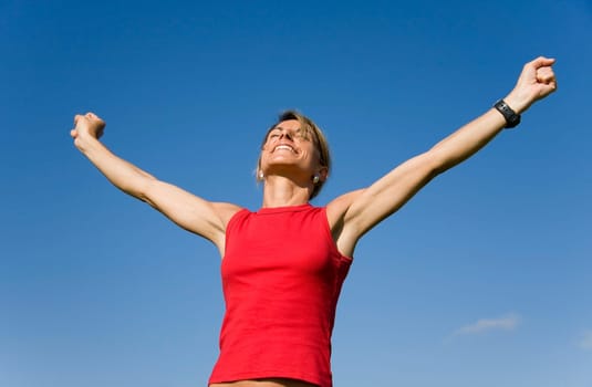 Beautiful women with her arms outstretched on a blue sky