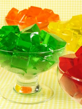 Glasses of orange, green, red, and yellow cubed gelatin.