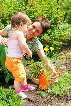 Baby girl helping mother in the garden