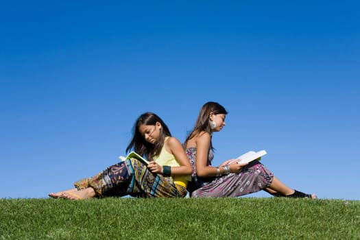 Two young girls reading isolated on blue sky