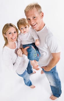 A young family is wearing white T-shirts and smiling up at the camera.  Vertically framed shot.