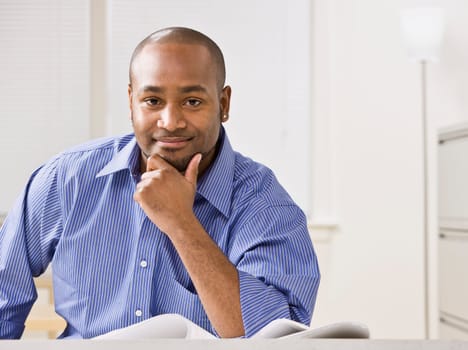 A young businessman is smiling at the camera.  Horizontally framed shot.