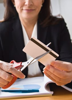 A businesswoman is cutting up a credit card with a pair of scissors.  Vertically framed shot.