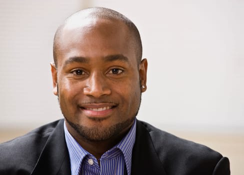 A young businessman is smiling at the camera.  Horizontally framed shot.
