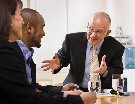 Business team meeting with two men and a woman sitting at a desk with water.  Horizontal