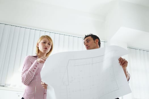 two architects examining blueprint indoors. Low angle view. Copy space