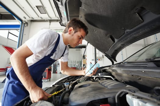 side view of mechanic checking motor oil