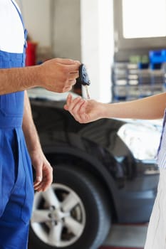 cropped view of mechanic giving car keys to female client
