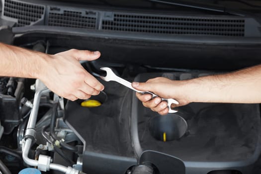 close up of two mechanics sharing metal spanner.