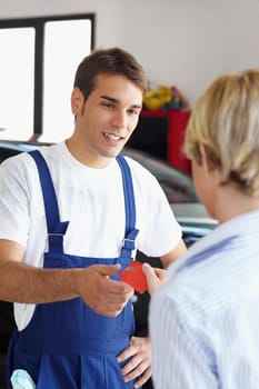 Rear view of woman giving credit card to mechanic.