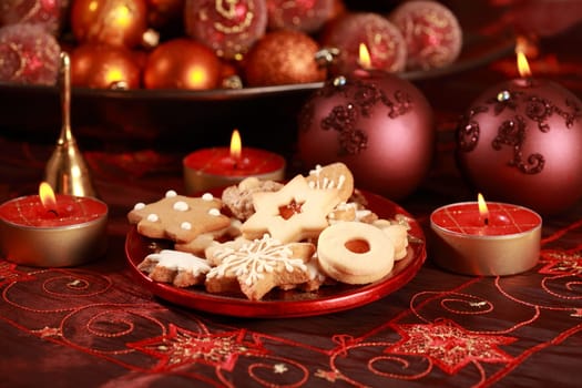 Detail of delicious Christmas cookies with candles in red tone
